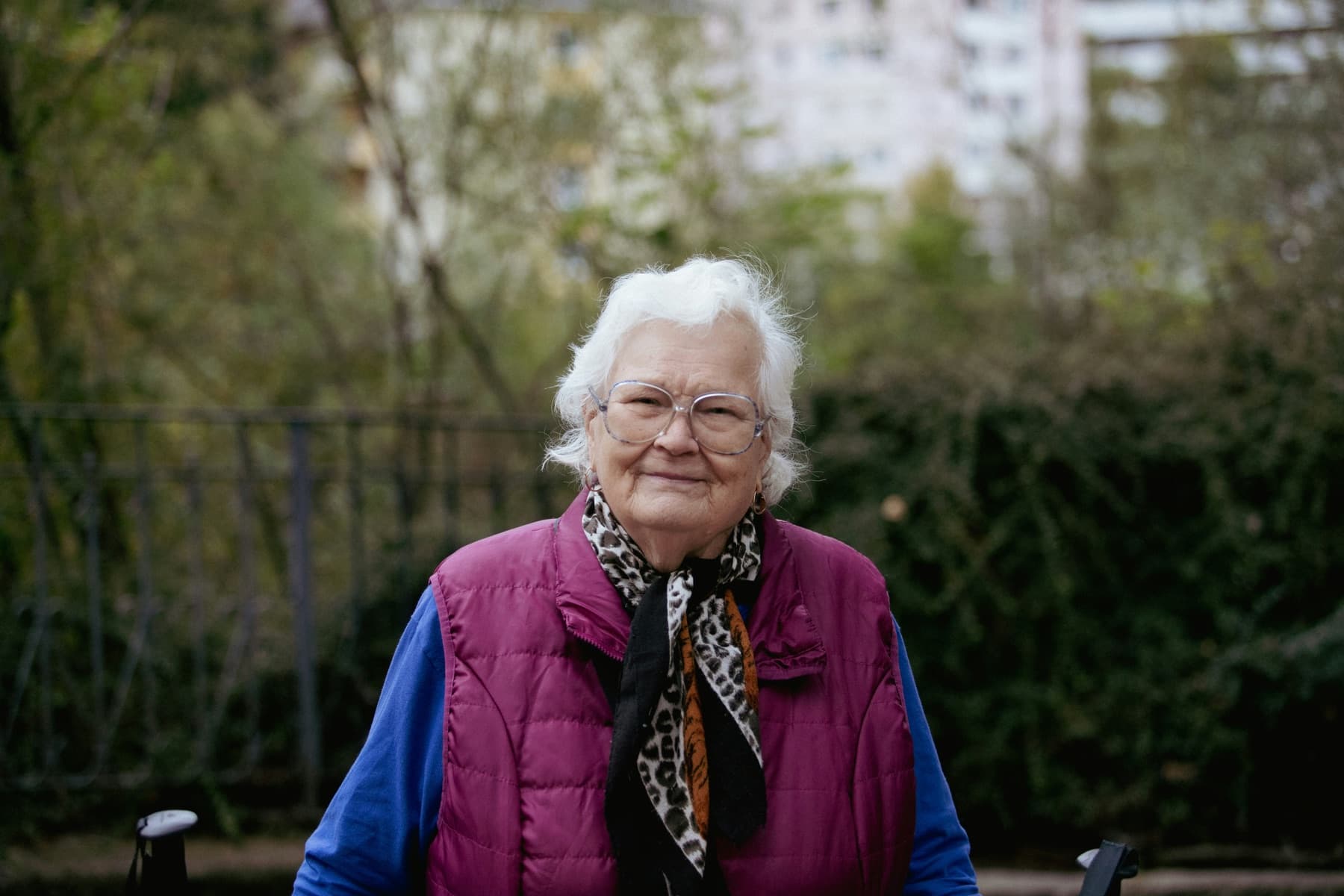 Dorothy, an older woman in glasses, smiling outside her home